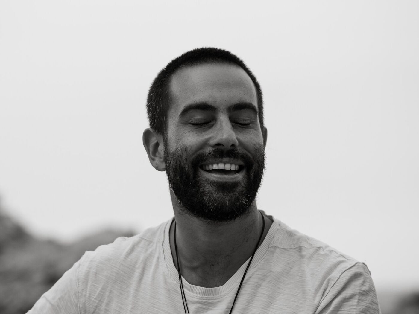 Sergi Colomer, terapeuta en psicosomàtica i biodescodificació, somrient amb els ulls tancats, en blanc i negre